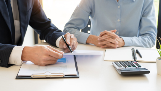 Two individuals reviewing paperwork at a desk.