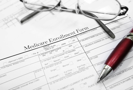 Medicare enrollment form with a pen and eyeglasses sitting on top.